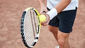 Nahaufnahme eines Tennisspielers beim Aufschlag.