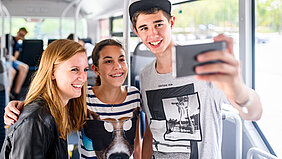Eine Gruppe fröhlicher junger Menschen macht ein gemeinsames Selfie im Bus.