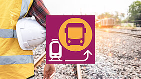 Gleisbauarbeiter mit Schutzhelm unter dem Arm von hinten, im Vordergrund das Logo für Schienenersatzverkehr mit Bussen.